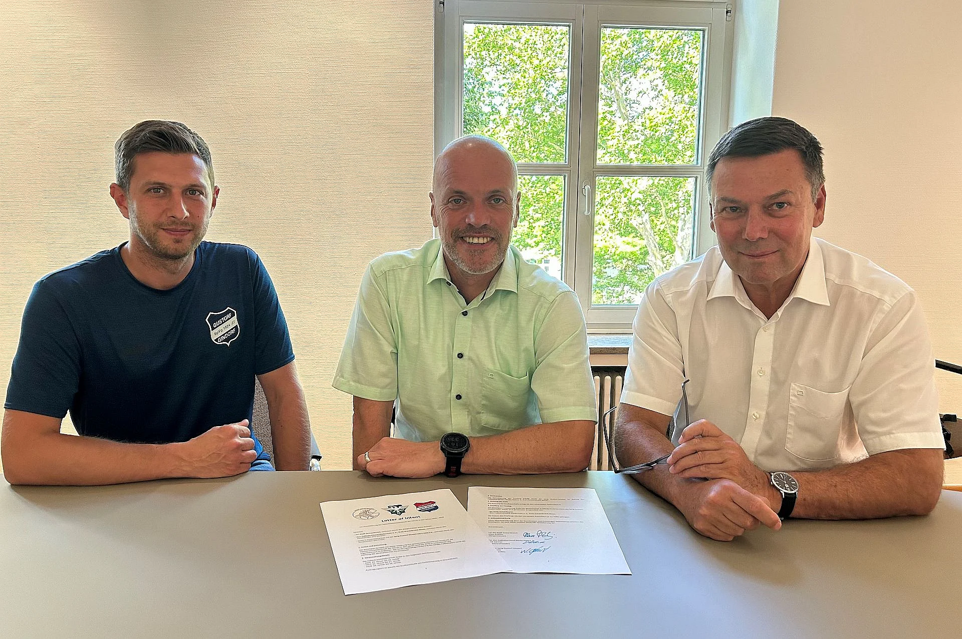 Das Foto zeigt: 1. Vorsitzender der SpVg Gustorf-Gindorf 1924/1927 e.V. Nils Fienitz, Bürgermeister Klaus Krützen und Vorsitzender des Fußballverbands Niederrhein e.V. Dirk Gärtner bei der Unterzeichnung der Absichtserklärung.