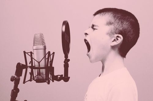Symbolbild: Junge, der in ein Mikro singt