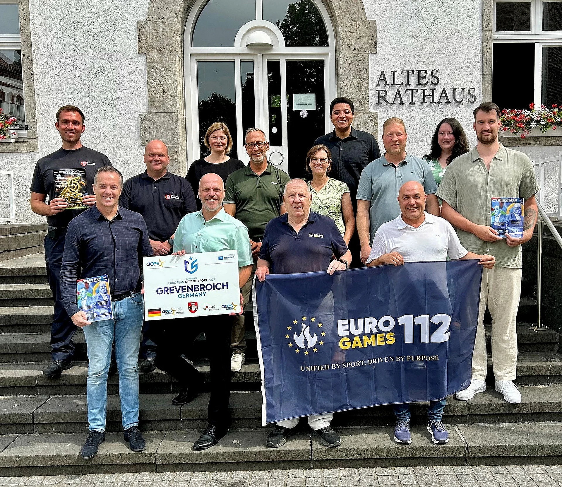 Foto von Jesús Peramos, Bürgermeister Klaus Krützen und Robert Thomas gemeinsam mit Vertreterinnen und Vertretern des Rhein-Kreises Neuss, der Feuerwehr, der Gesellschaft für Wirtschaftsförderung und Stadtmarketing sowie des Sportamtes