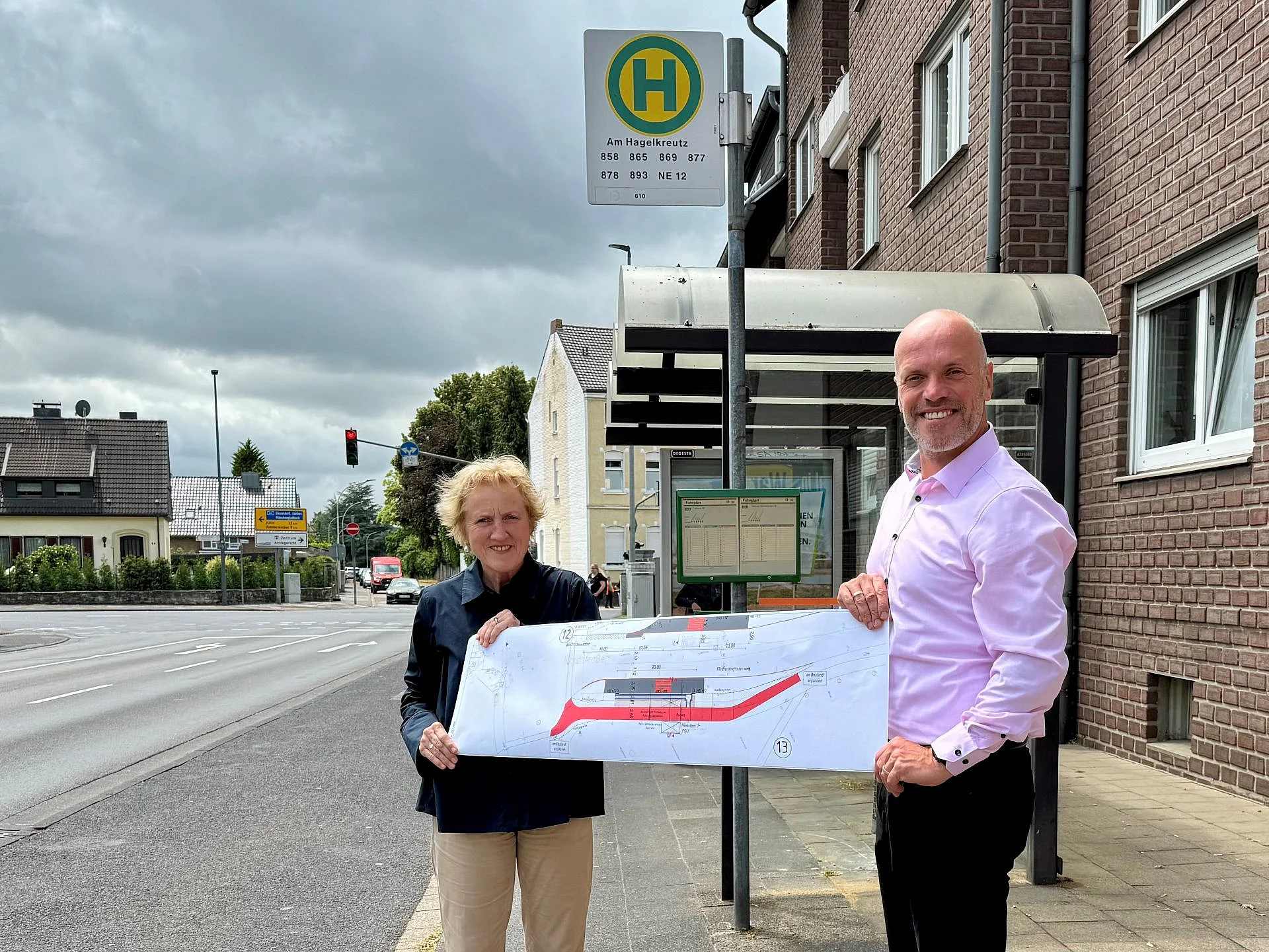 Bürgermeister Klaus Krützen und Monika Stirken-Hohmann, Vorständin der Stadtbetriebe Grevenbroich AöR, präsentieren die Planskizze zum barrierefreien Umbau der Bushaltstelle „Am Hagelkreuz“