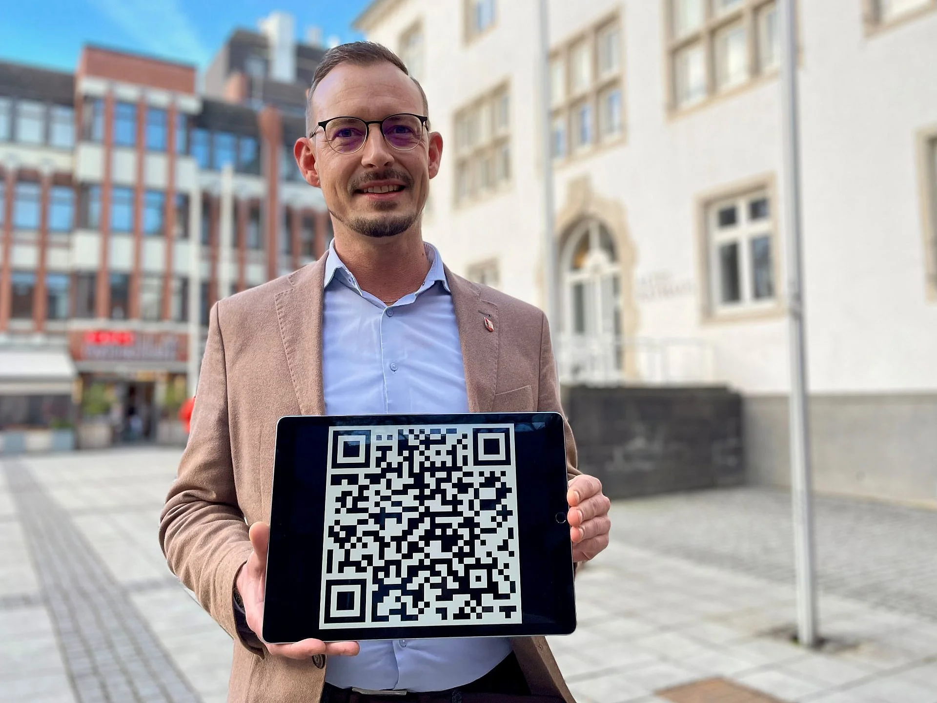 Foto des Smart-City-Managers Christian Henicke und QR-Code zur Umfrage